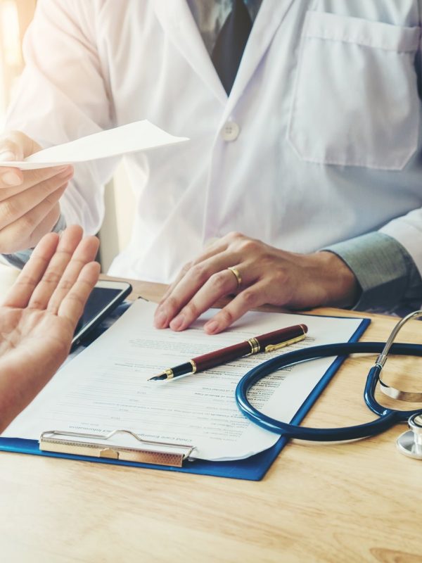 Doctor or physician writing diagnosis and giving a medical prescription to female Patient